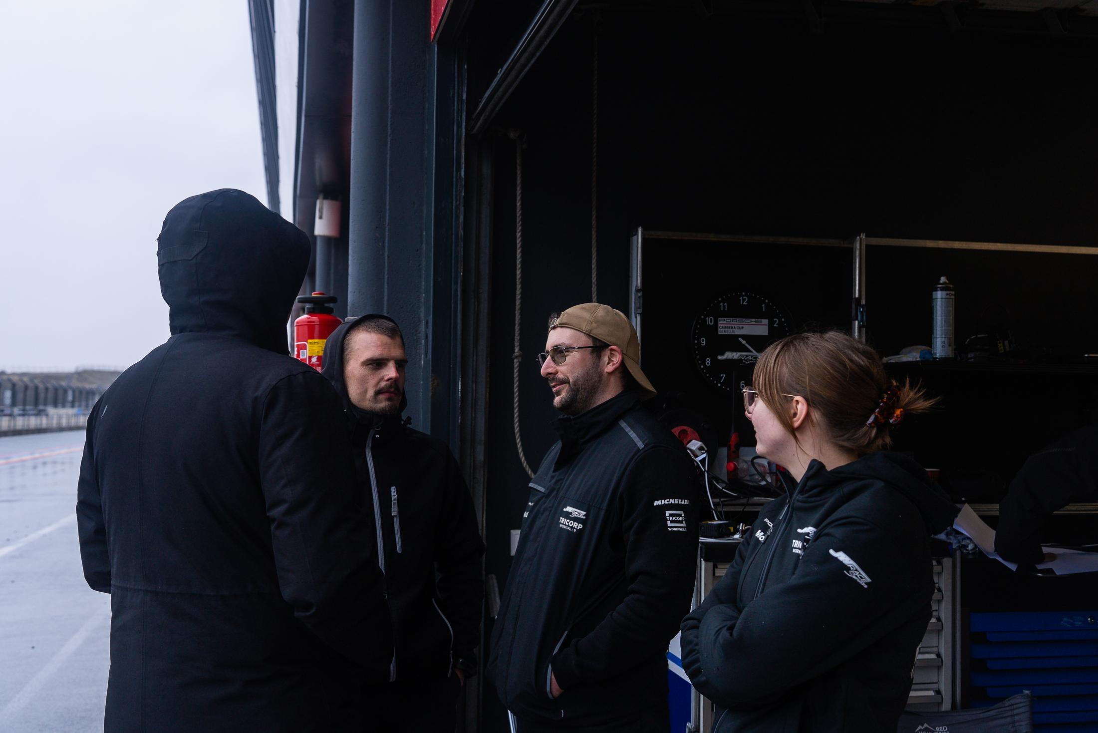 Sia talking with team members in a pit garage